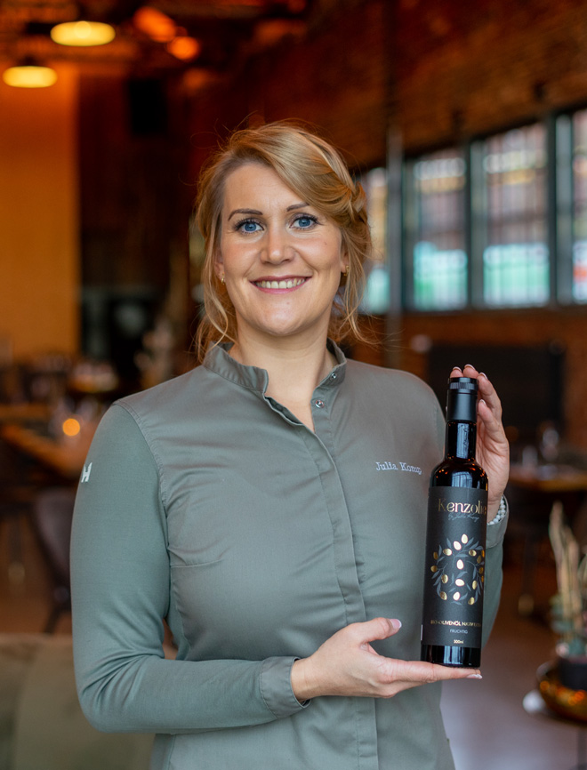 Sterneköchin Julia Komp trägt eine Bio Olivenöl Flasche Kenzolie